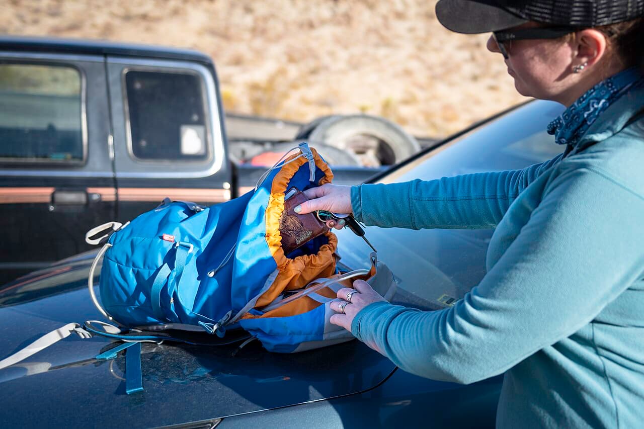 A traveler packing a backpack before setting out on a hike.